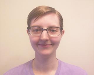 White person with short blonde hair, glasses, and a light purple shirt